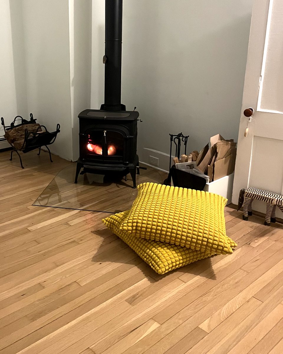 The same corner after refinishing, with the floor one even color and a wood stove in place