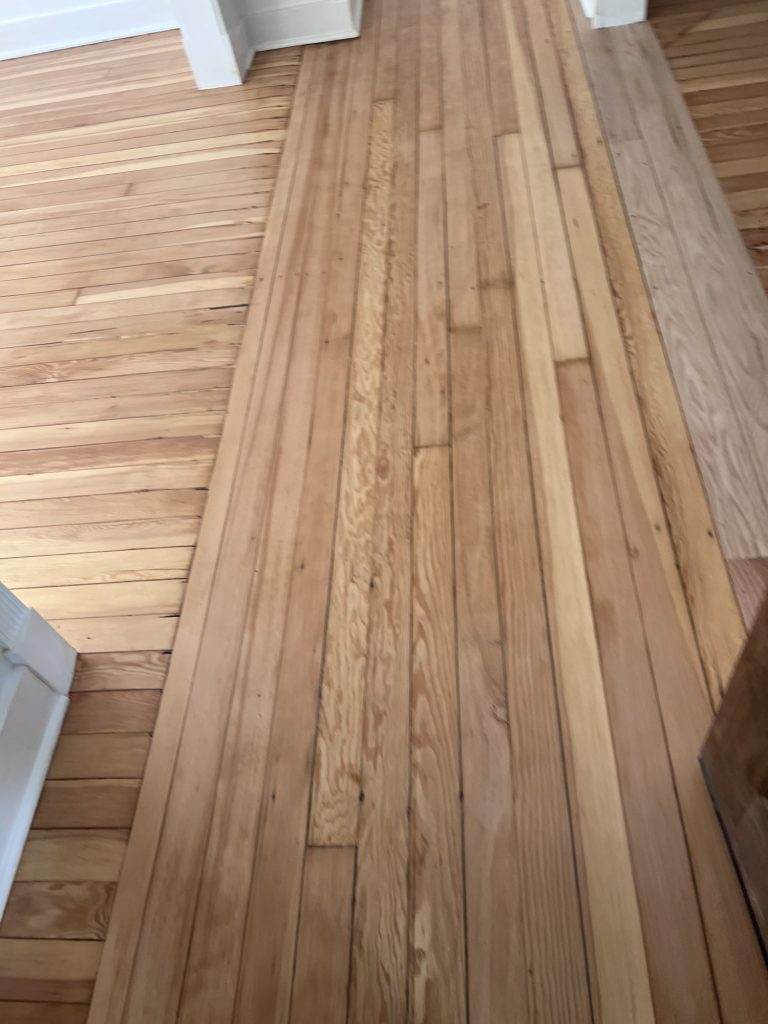 Close-up of refinished wood floor boards showing the grain under a natural finish