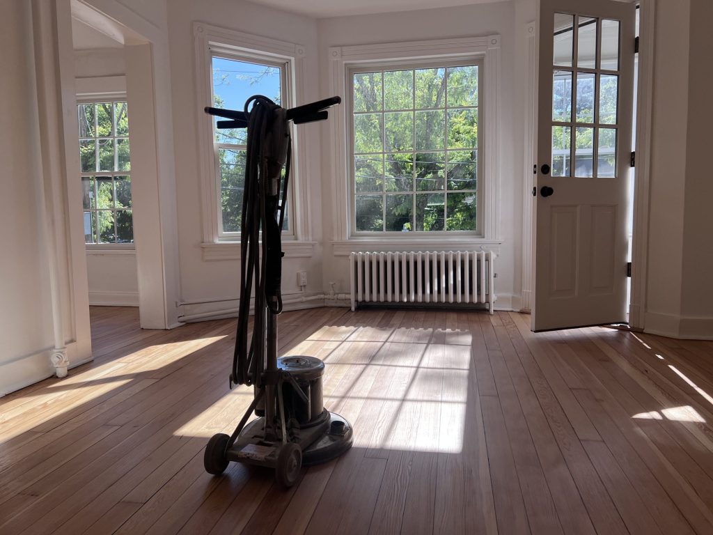 Floor buffer in the middle of a freshly refinished room with bay windows